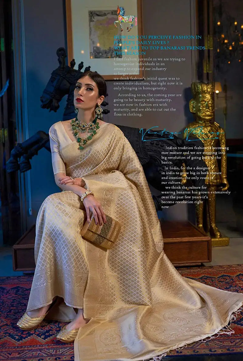 Woman in a beige saree sitting on a decorative rug with text overlay