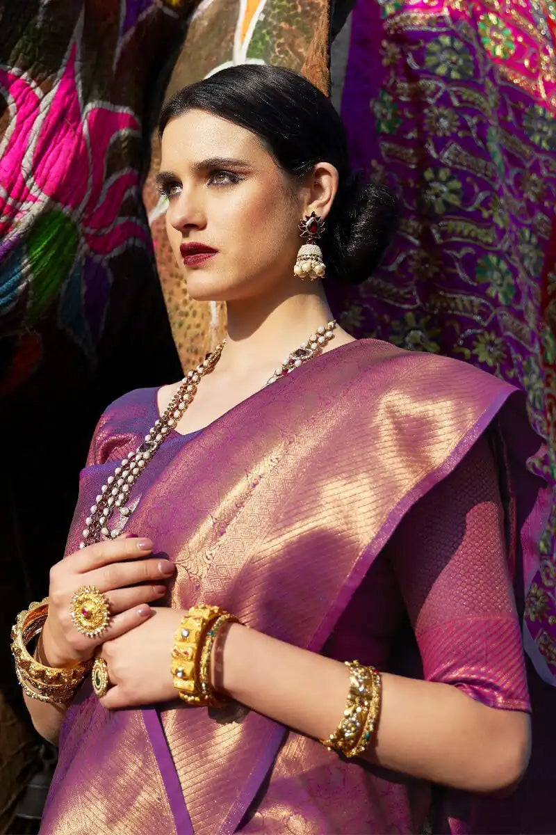 Woman in a traditional pink saree with jewelry against a colorful background