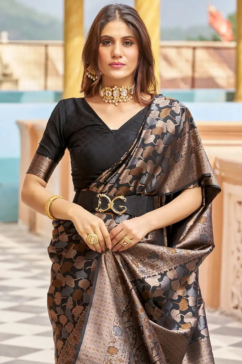 Woman wearing a black and gold saree with jewelry outdoors.