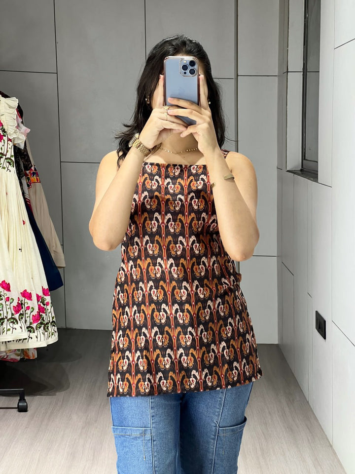 Person wearing a patterned top and blue jeans taking a mirror selfie.