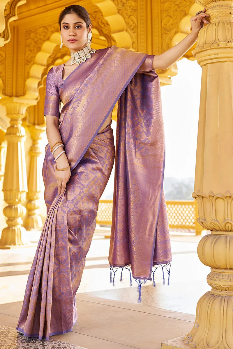 Woman in a traditional purple saree standing in front of a golden architectural background