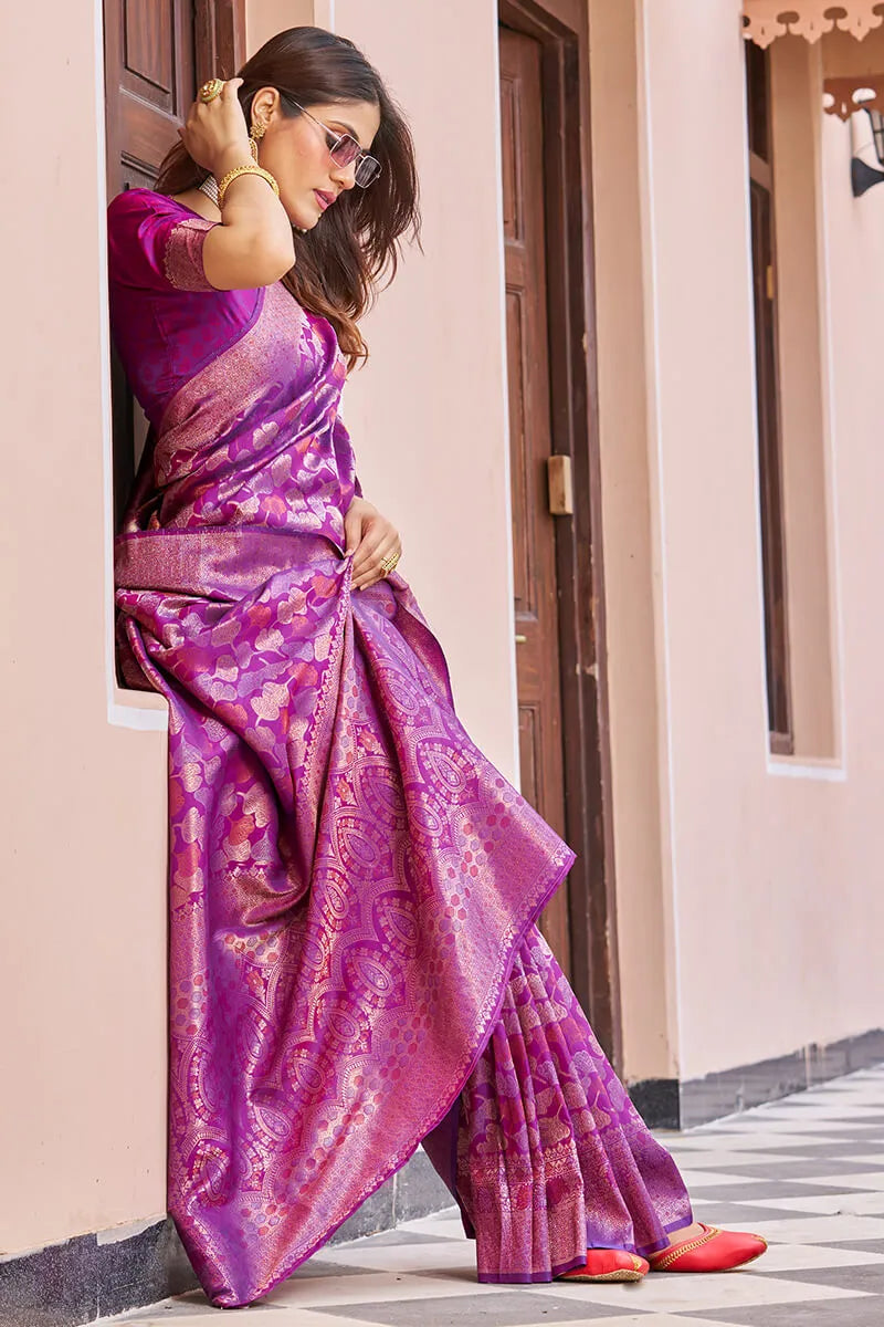 Woman in a purple saree standing outside a building