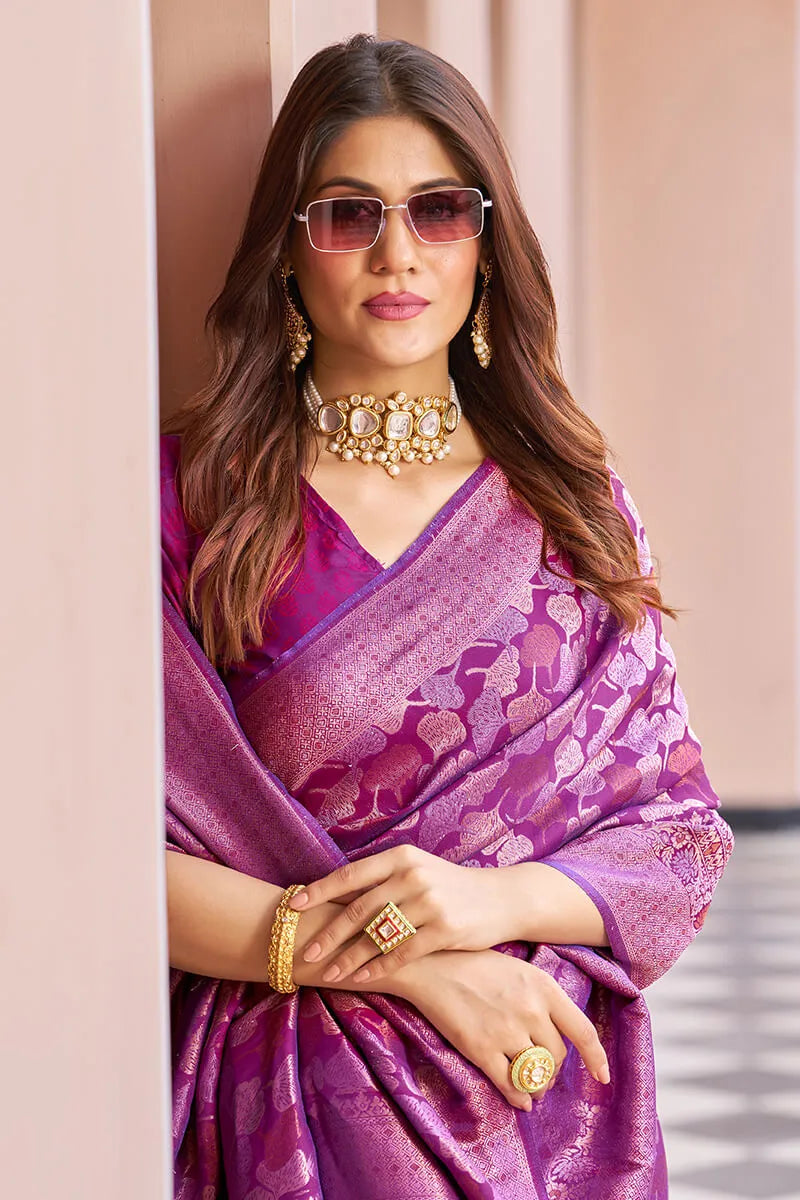 Woman wearing a purple saree with gold jewelry indoors