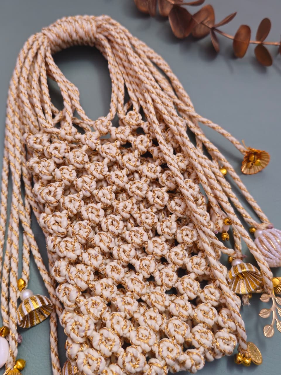 Beige woven bag with decorative elements on a gray background