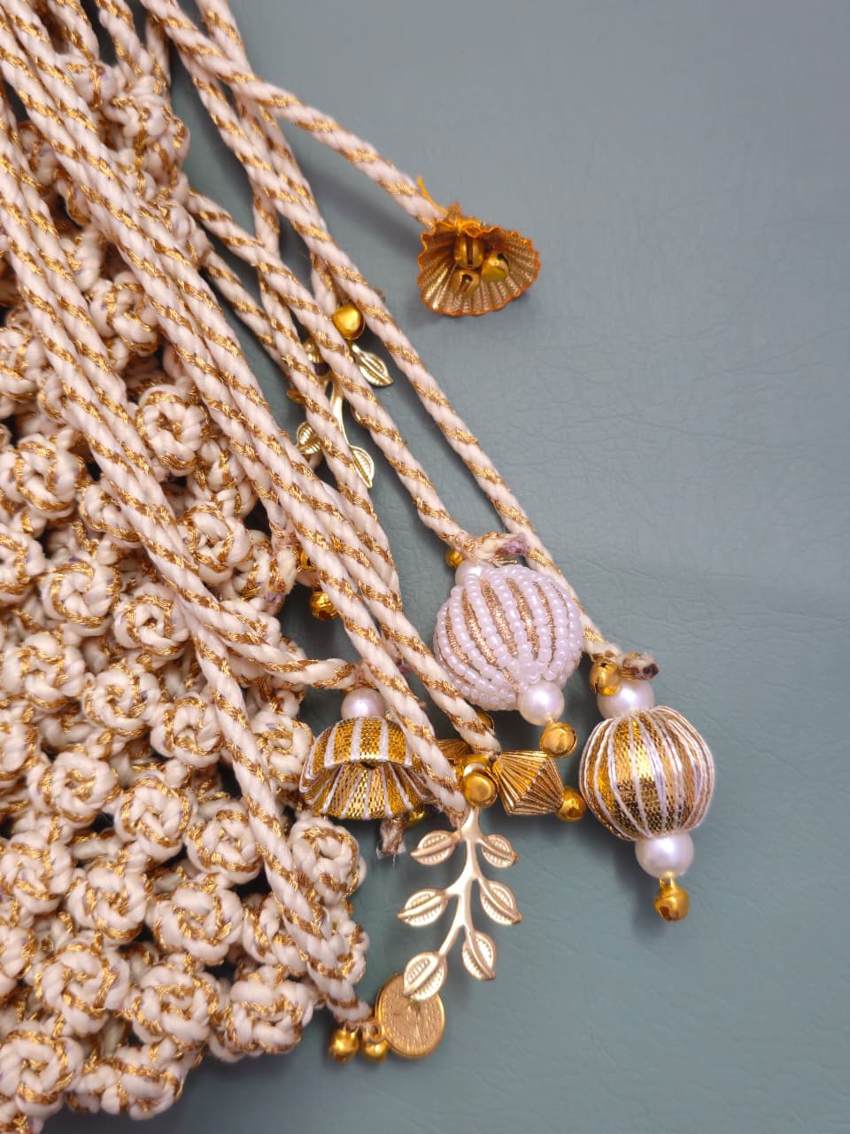 Decorative gold and beige tassel with beads on a gray background