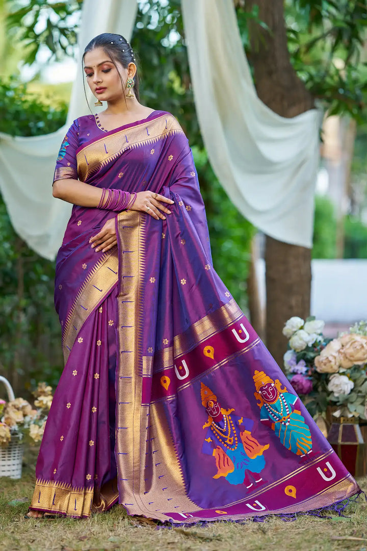 Woman wearing a traditional purple saree with gold and multicolor patterns, standing outdoors.
