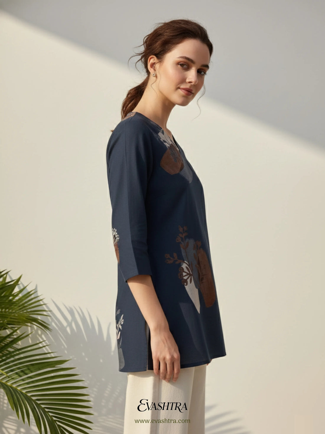 Woman wearing a navy blue embroidered top with a white background and 'Evashira' branding.