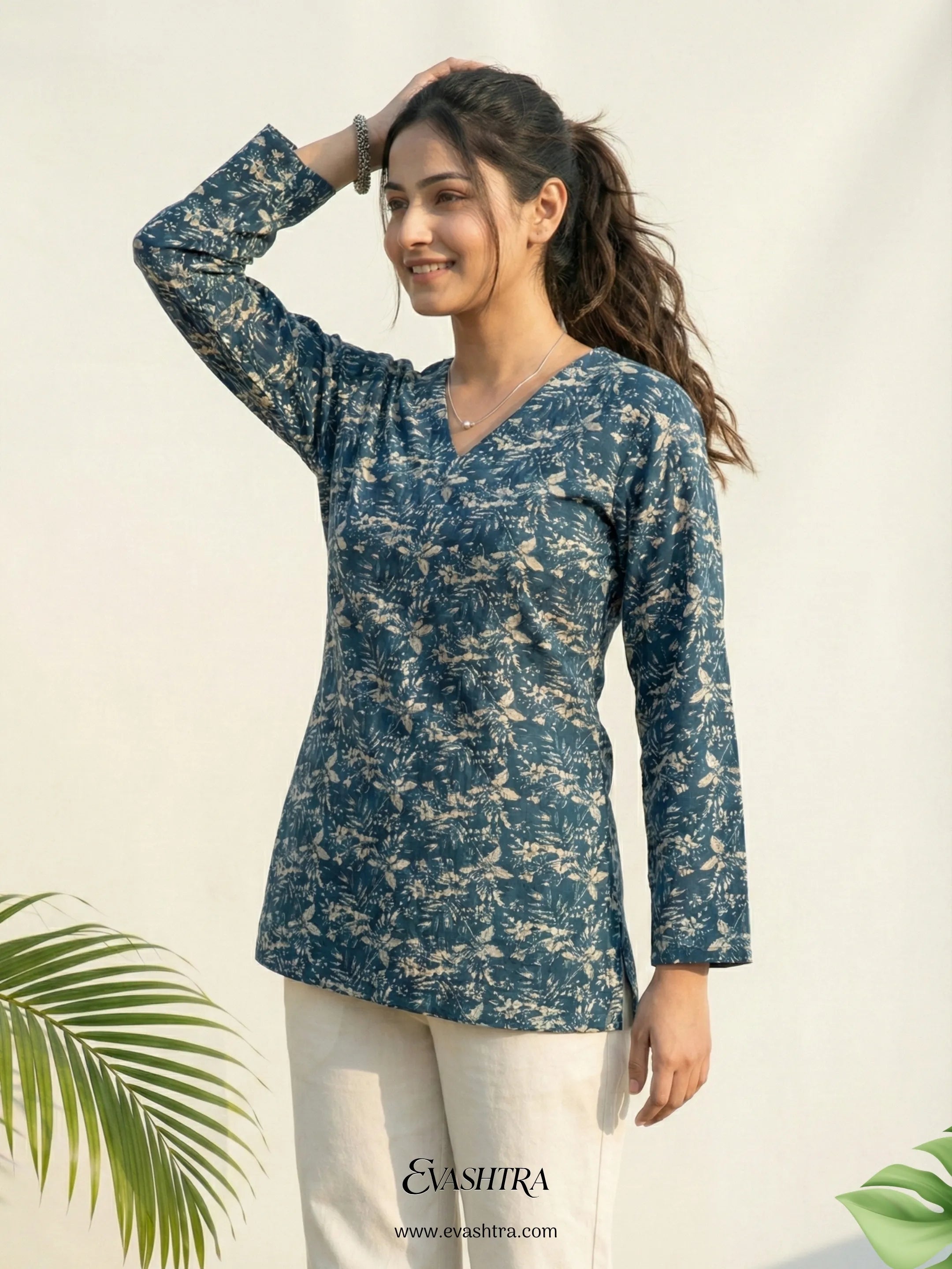 Woman wearing a blue floral top with a white background and green leaves.