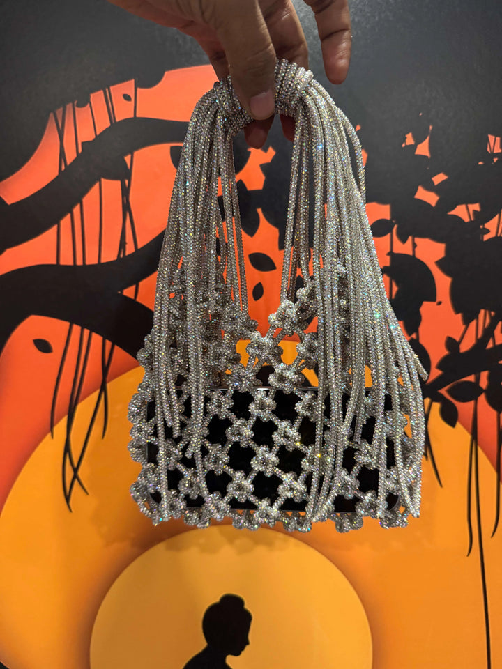 Hand holding a beaded bag against an abstract orange and black background