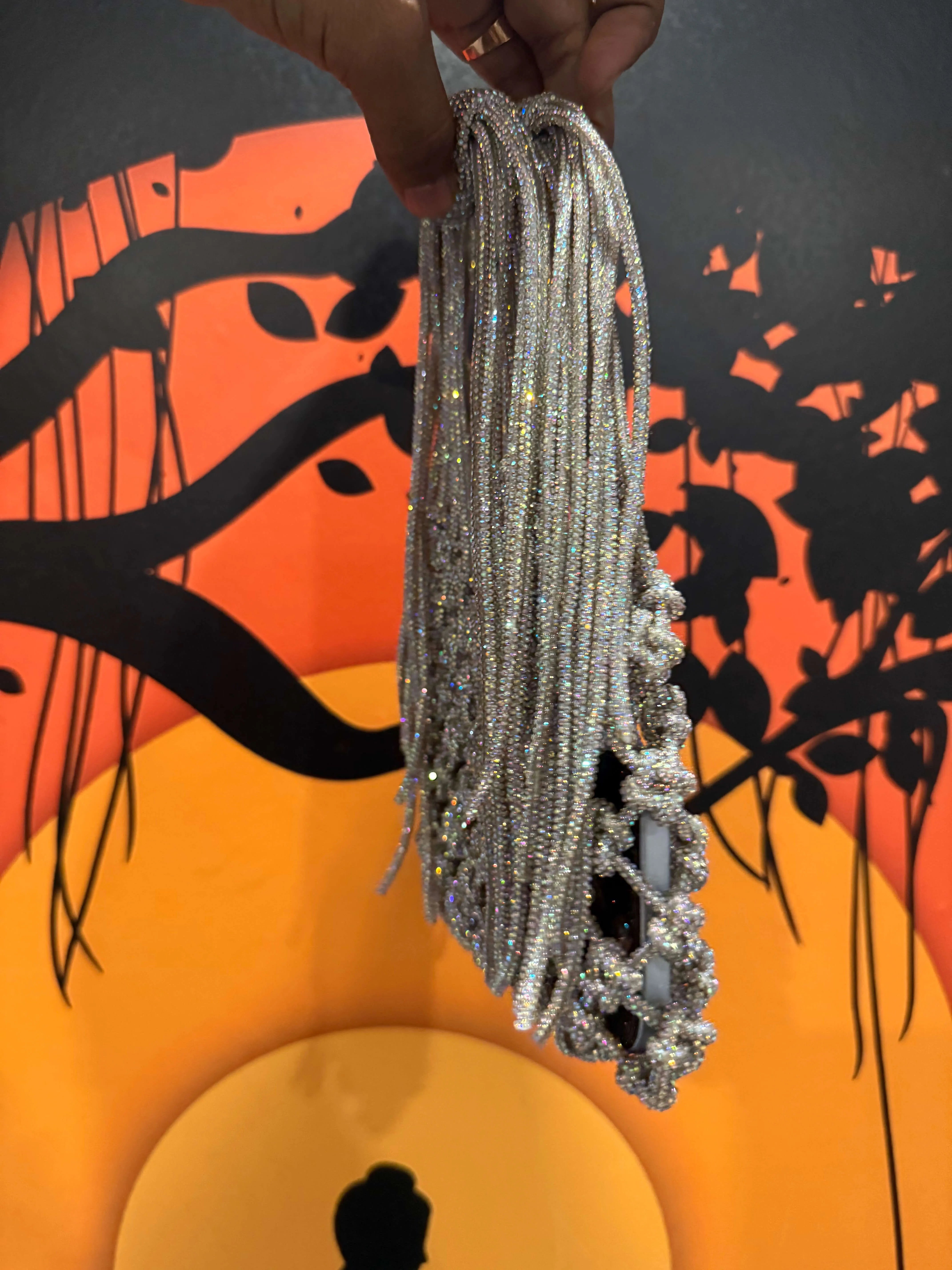 Silver beaded necklace held against a colorful abstract background