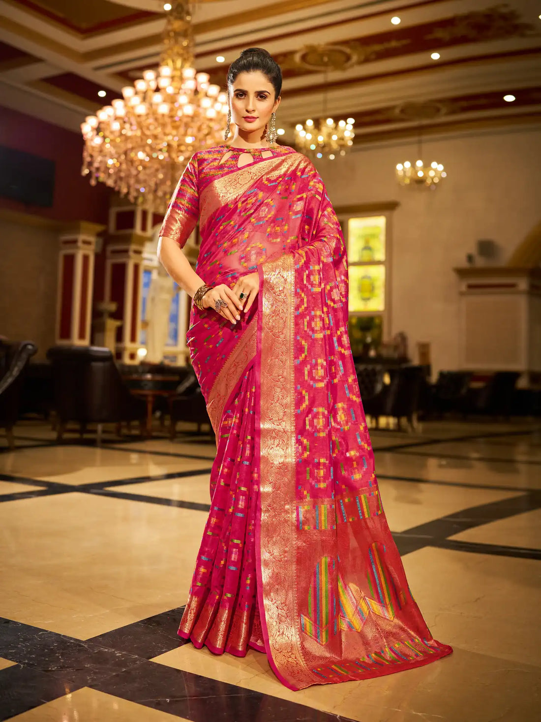 Woman in a pink saree with gold patterns in an elegant indoor setting