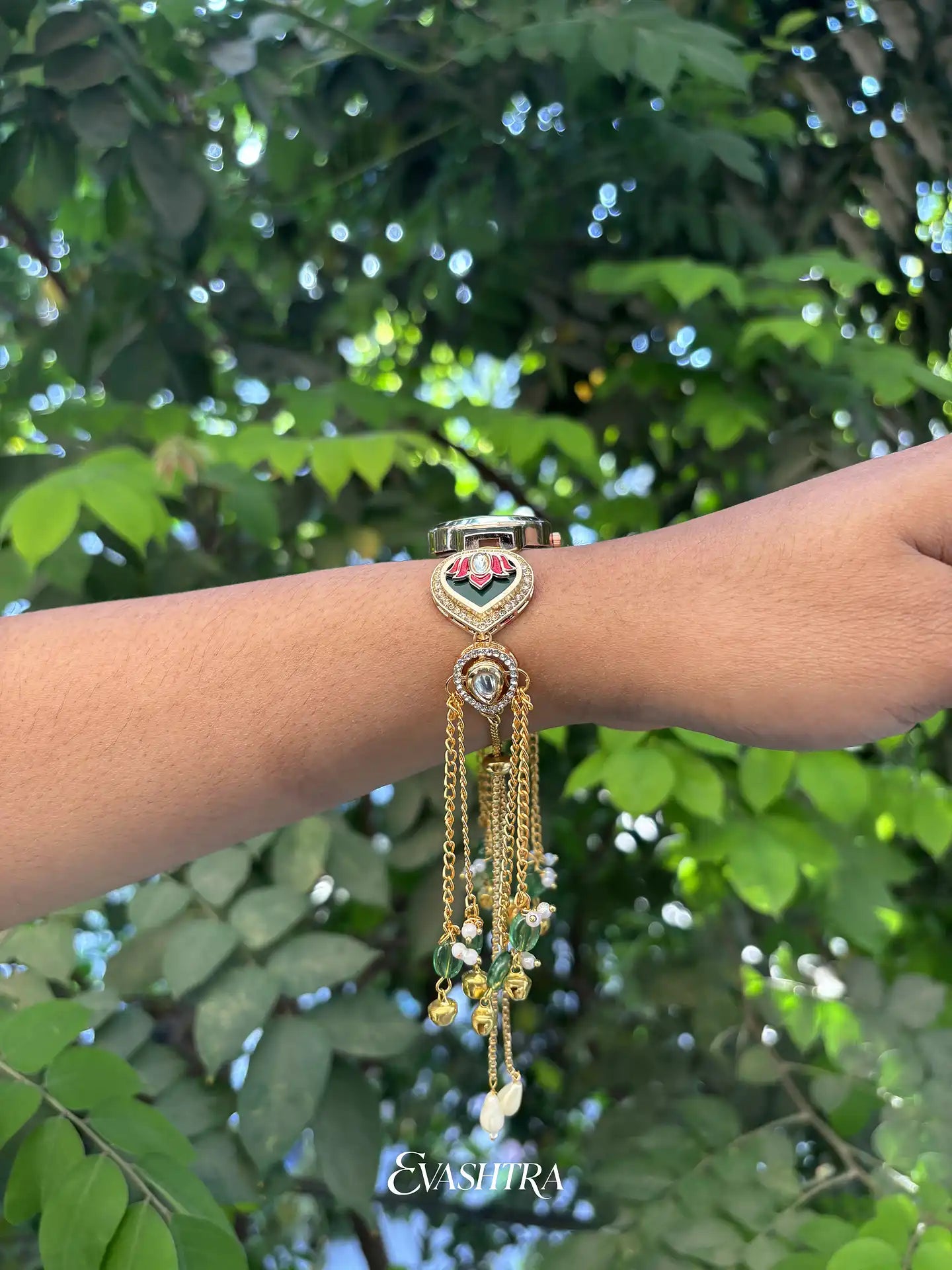 Bracelet with decorative elements on a wrist against a green leafy background